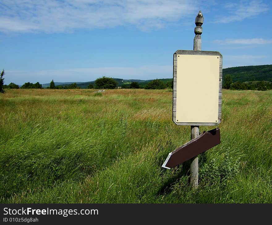 Wooden sign with arrow on green field. Wooden sign with arrow on green field