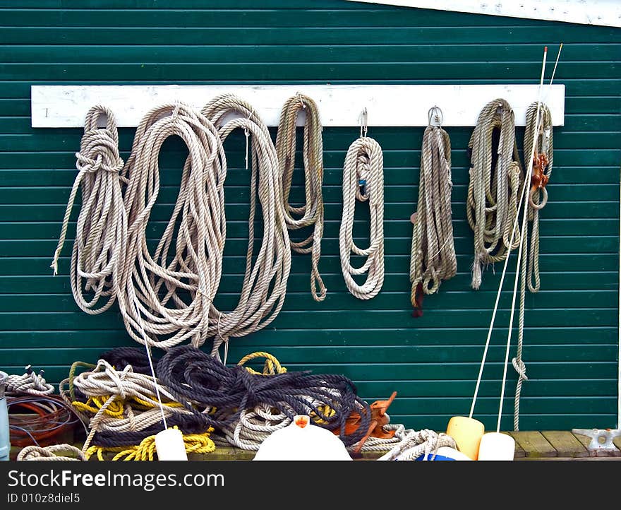 View of various ropes hanging and others on the ground in a fishing harbor.