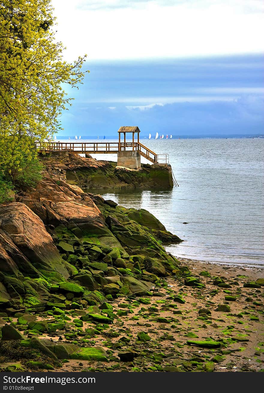 Seascape of rocky shore with distant sail boats. Seascape of rocky shore with distant sail boats.