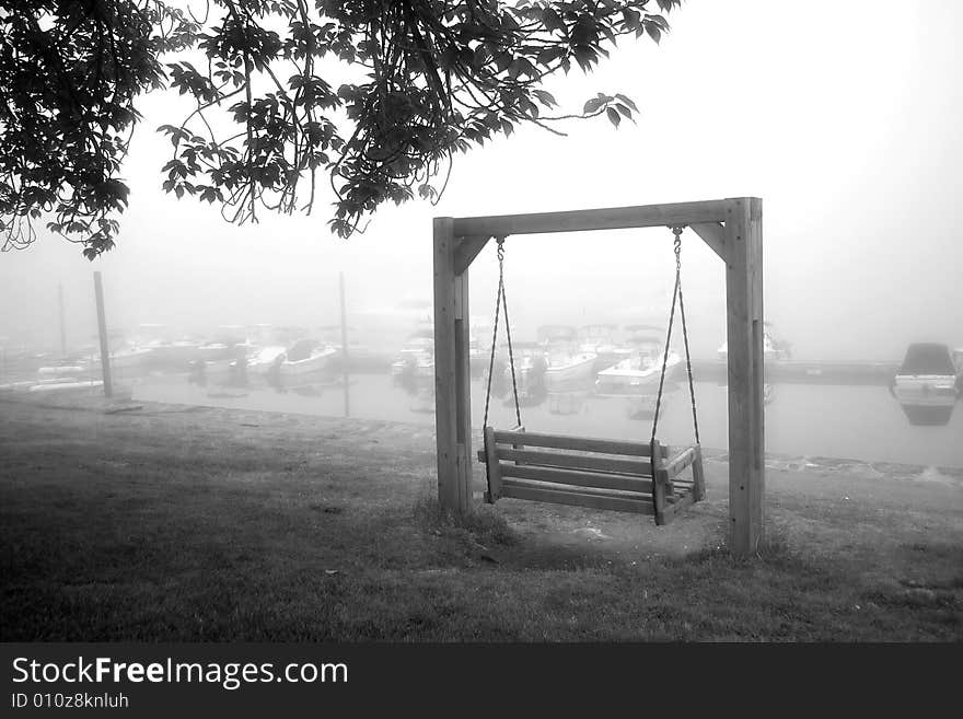 View of foggy marina and empty wooden swing. View of foggy marina and empty wooden swing