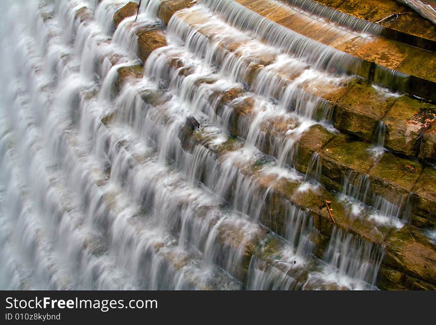 View of reservoir spillway with water tumbling over cement steps.