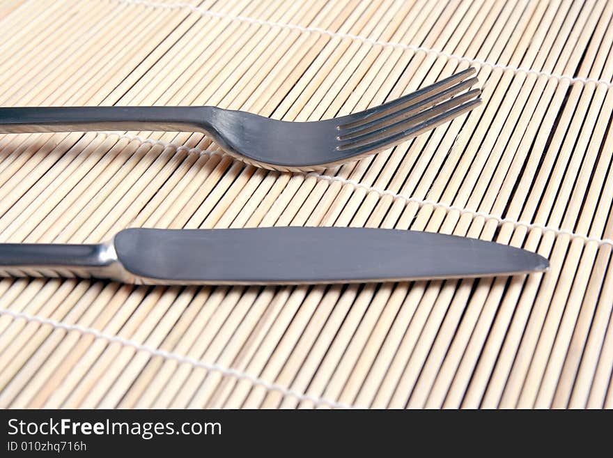 Knife and fork on kitchen  bamboo mat. Knife and fork on kitchen  bamboo mat