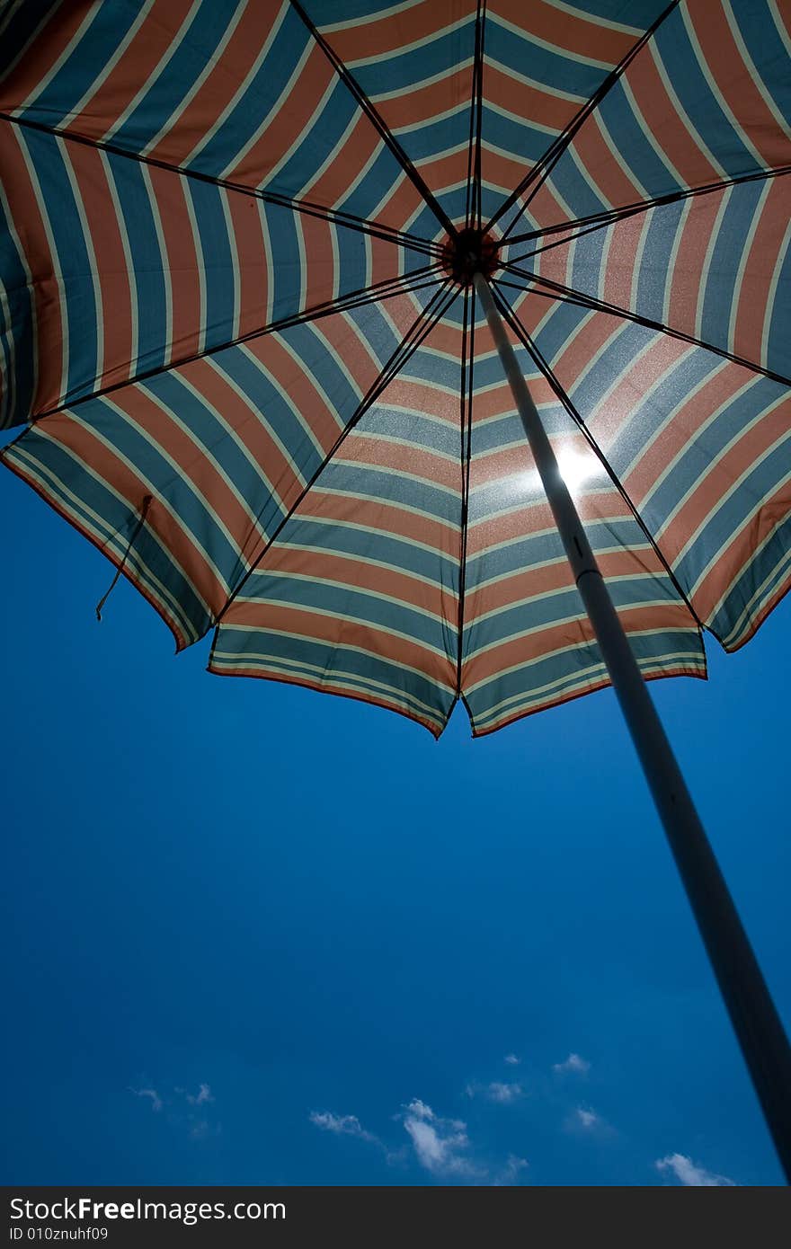 Beach umbrella is displayed against a background of blue Sky. Beach umbrella is displayed against a background of blue Sky