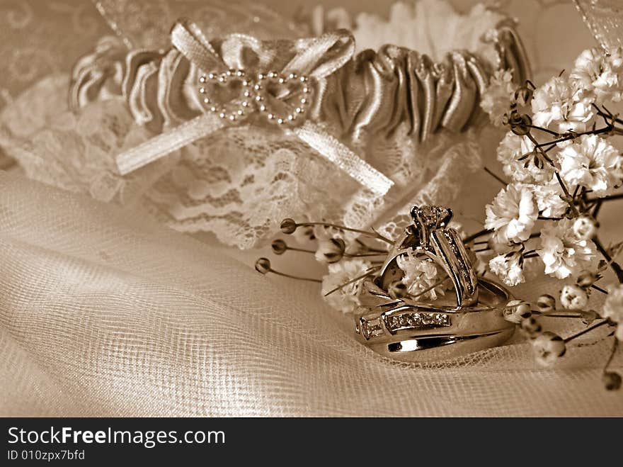 Wedding rings and garter on tulle in sepia. Wedding rings and garter on tulle in sepia.