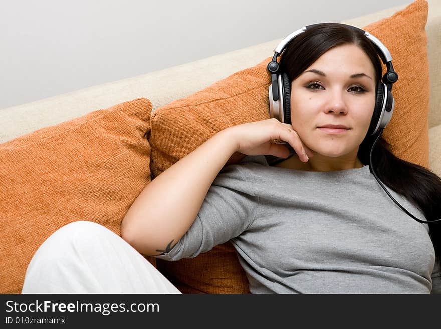 Attractive brunette woman with headphones on sofa. Attractive brunette woman with headphones on sofa