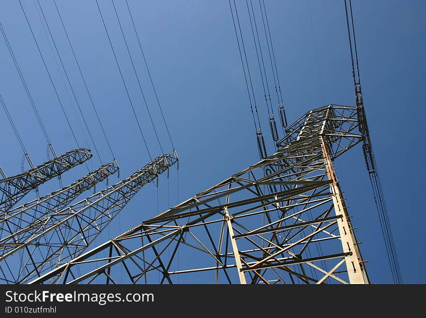 Towers and high tension lines against a blue sky. Towers and high tension lines against a blue sky