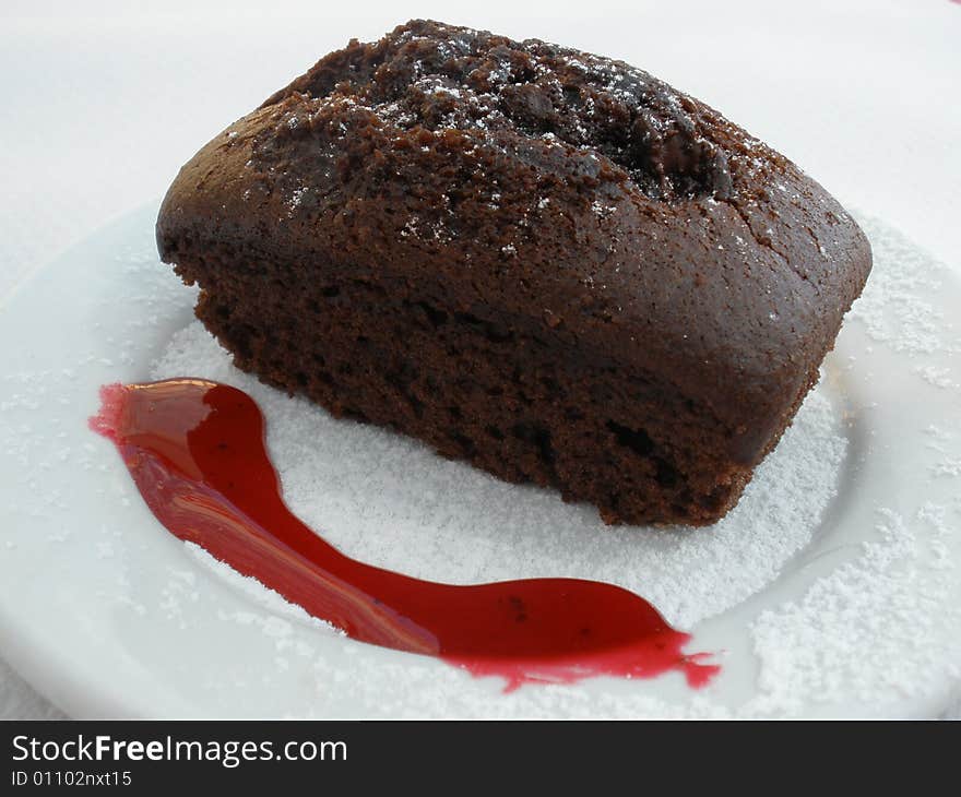 Chocolate cake with strawberry syrup and sugar glaze over white plate