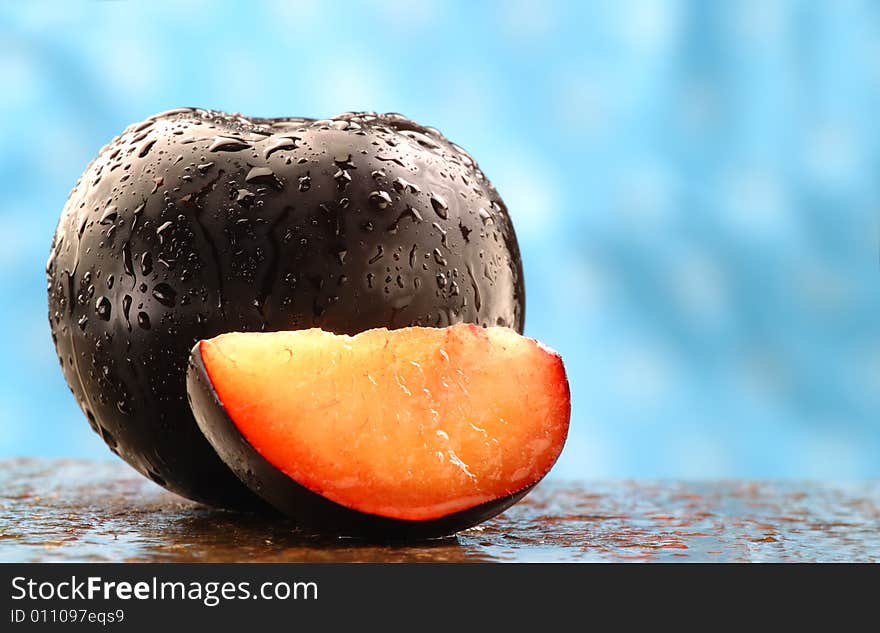 Fresh black plums on a stone counter.