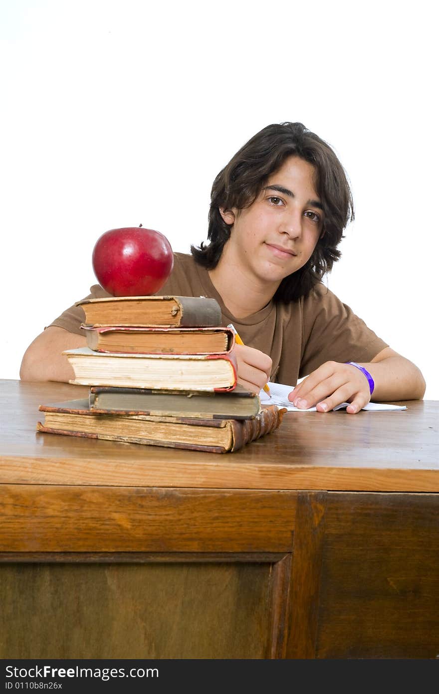 Teenager boy sitting by his desk with a red apple on pile of books. Teenager boy sitting by his desk with a red apple on pile of books