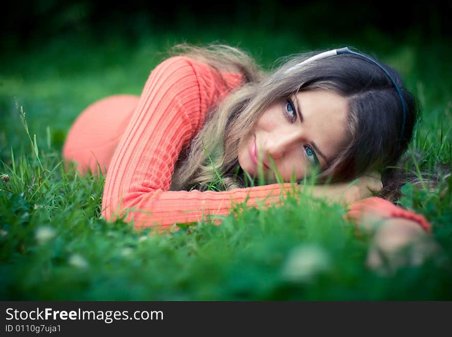 Relaxed young woman listening music cat clover meadow