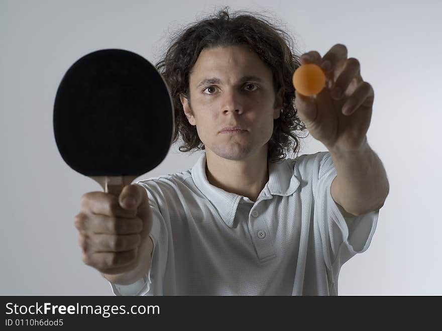 Man holding a table tennis ball and paddle out in front of him with a serious look on his face. Horizontally framed photograph. Man holding a table tennis ball and paddle out in front of him with a serious look on his face. Horizontally framed photograph