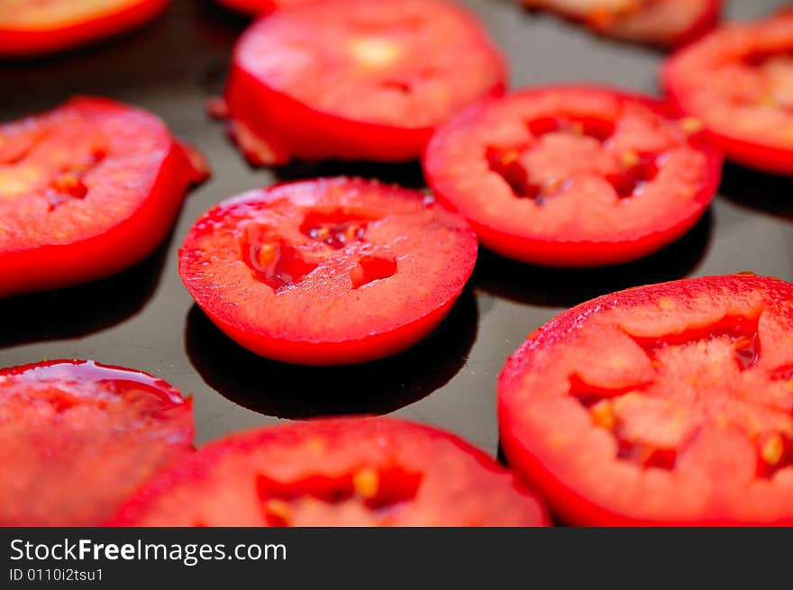 Sliced tomatoes composition on a dark desk. Sliced tomatoes composition on a dark desk