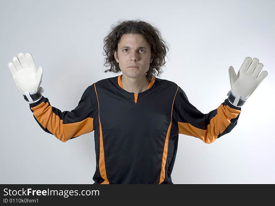 Soccer goalie wearing gloves looks serious as he has his hands out. Horizontally framed photograph. Soccer goalie wearing gloves looks serious as he has his hands out. Horizontally framed photograph.