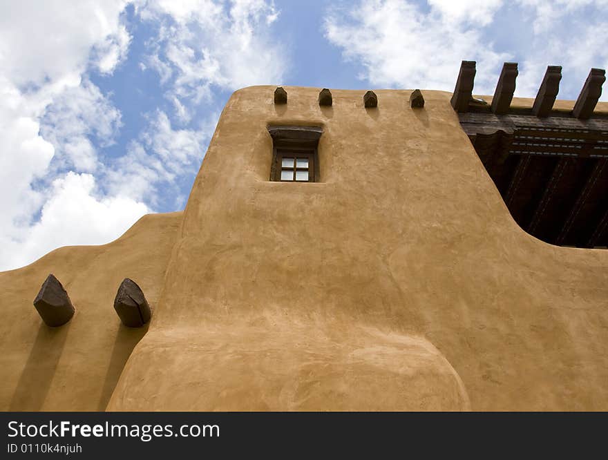 Adobe building with exposed wood beams under a blue sky