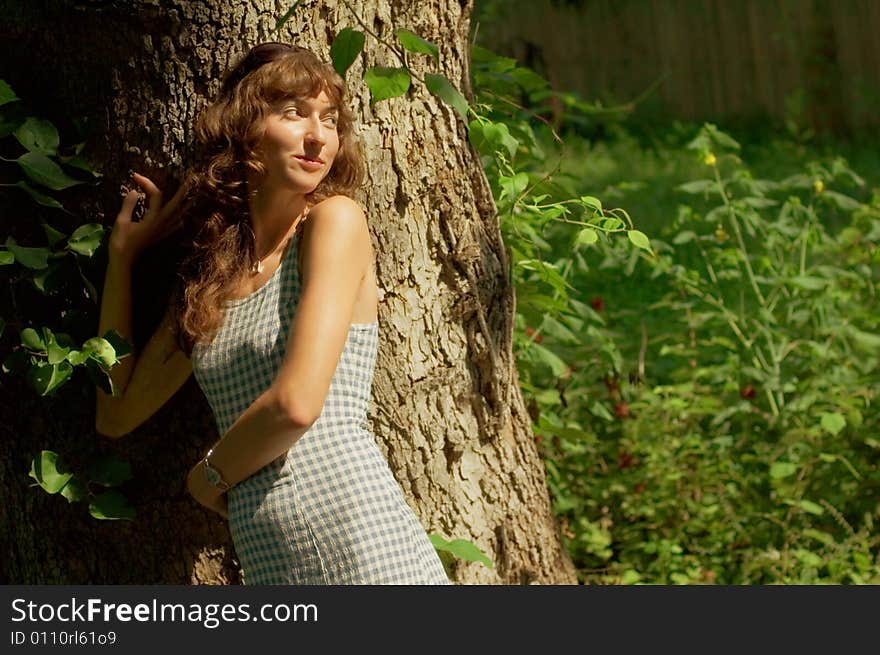 Sexy girl against tree trunk in woods.