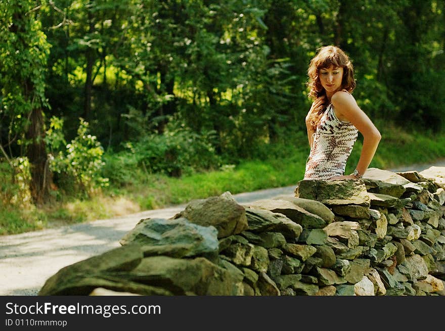 Pretty girl next to stone fence.