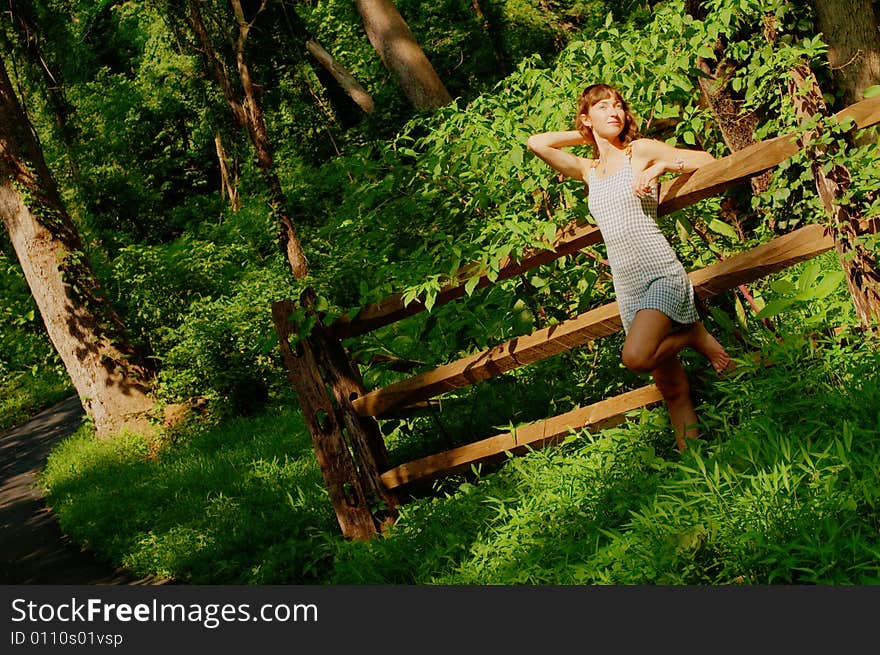 Pretty girl leaning against fence in woods. Pretty girl leaning against fence in woods.