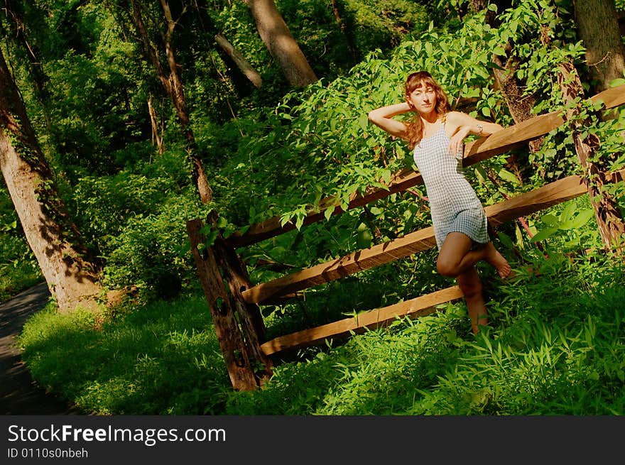 Pretty girl leaning against fence in woods. Pretty girl leaning against fence in woods.