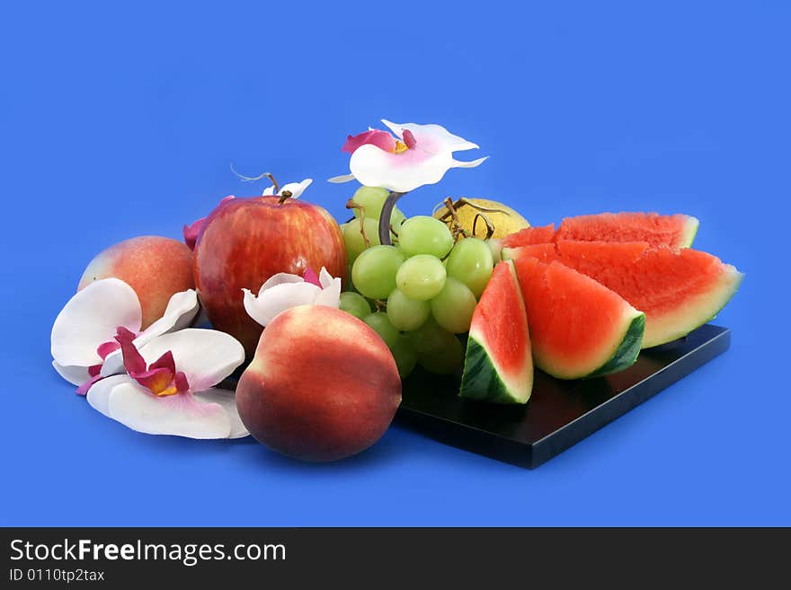 Composition from fruit, baccas of a lemon and an orchid on a black support. Composition from fruit, baccas of a lemon and an orchid on a black support