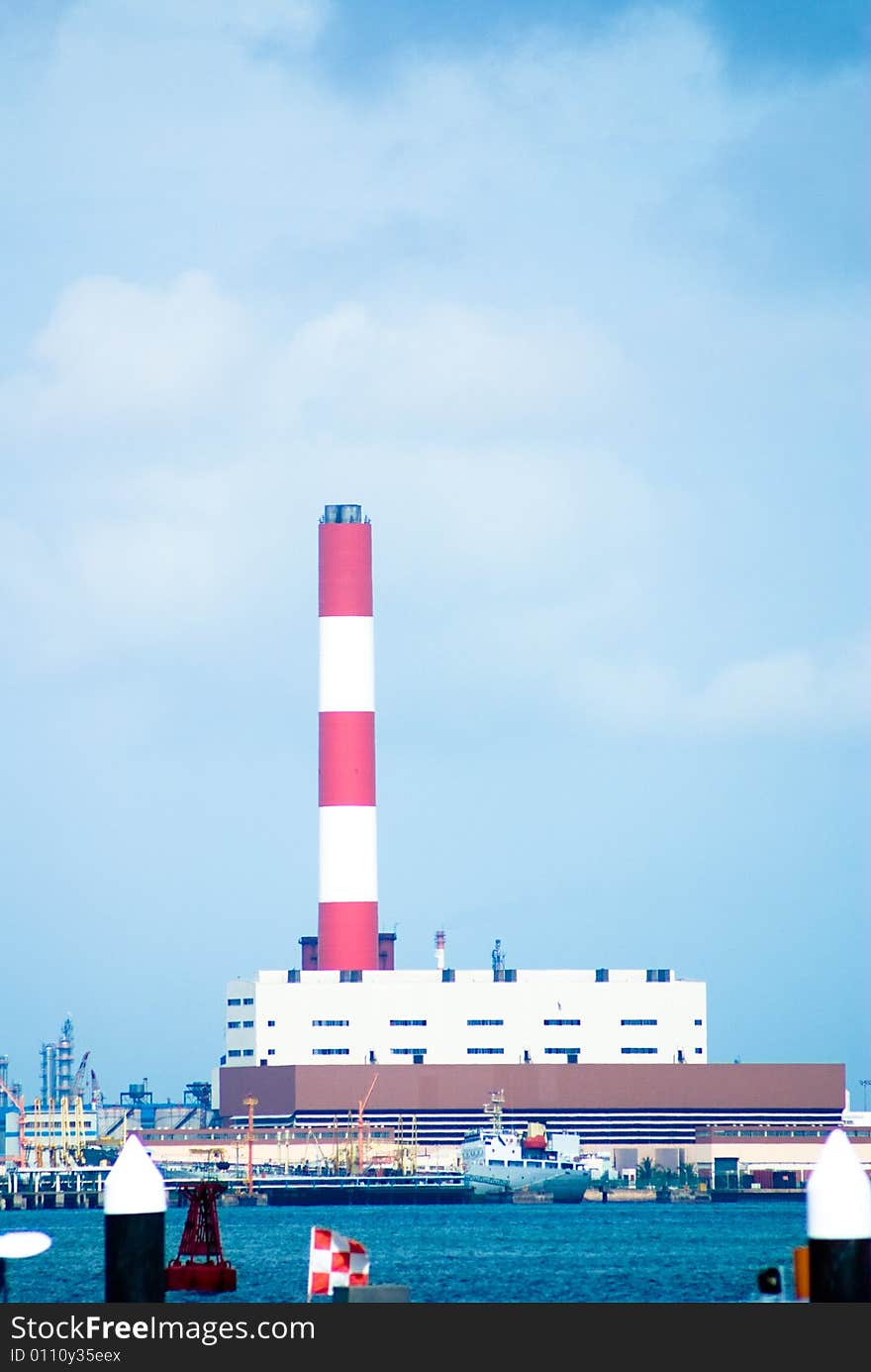 Industrial chimney in red and white color around a habor area.