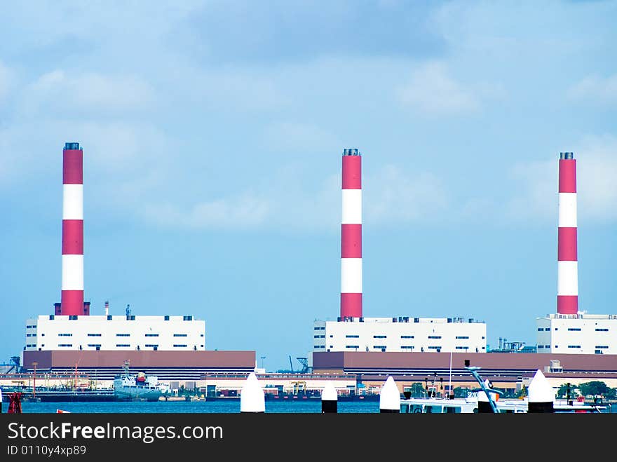 Industrial chimney in red and white color around a habor area.