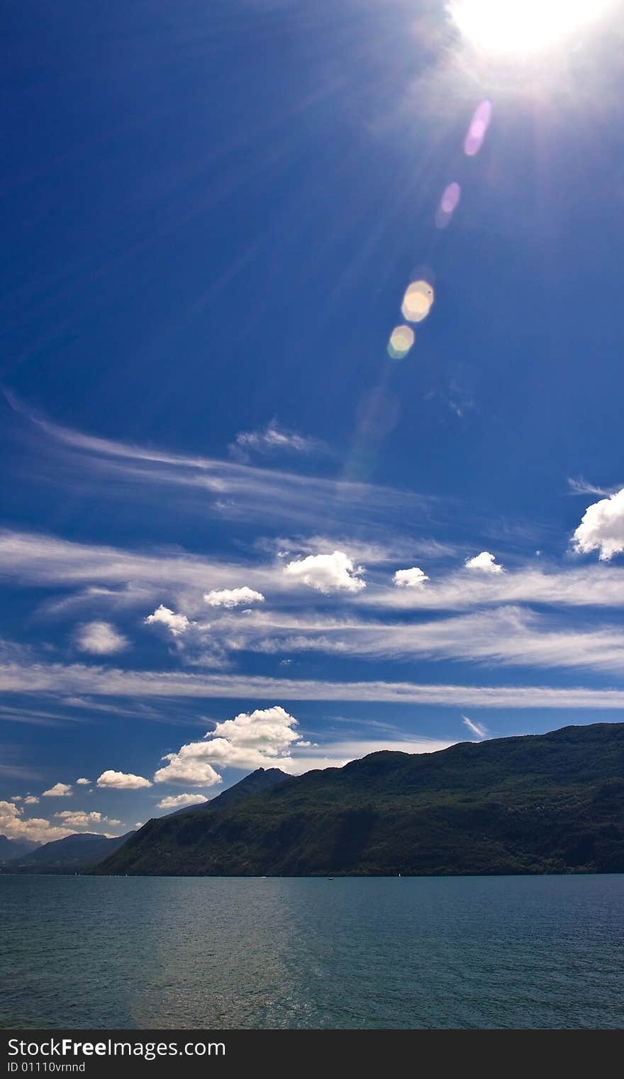 Sunny day over lake and mountains - sun beams and lens flare