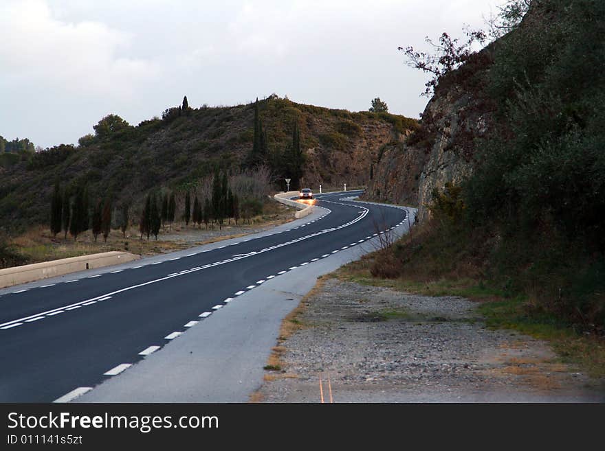 Road curves with a car at sunrise