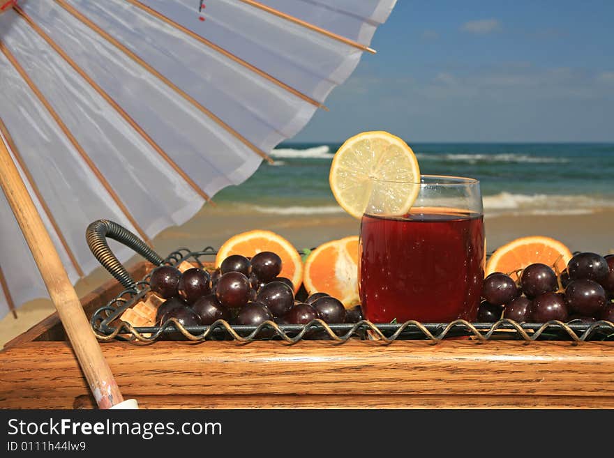 Glass of vine juice with the lobule of lemon and fruits  on a background a sea-piece