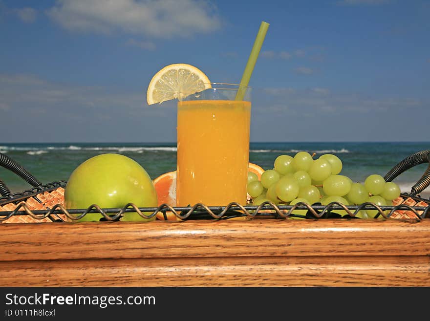 Glass of orange juice in surroundings fresh fruits on a background a sea-piece