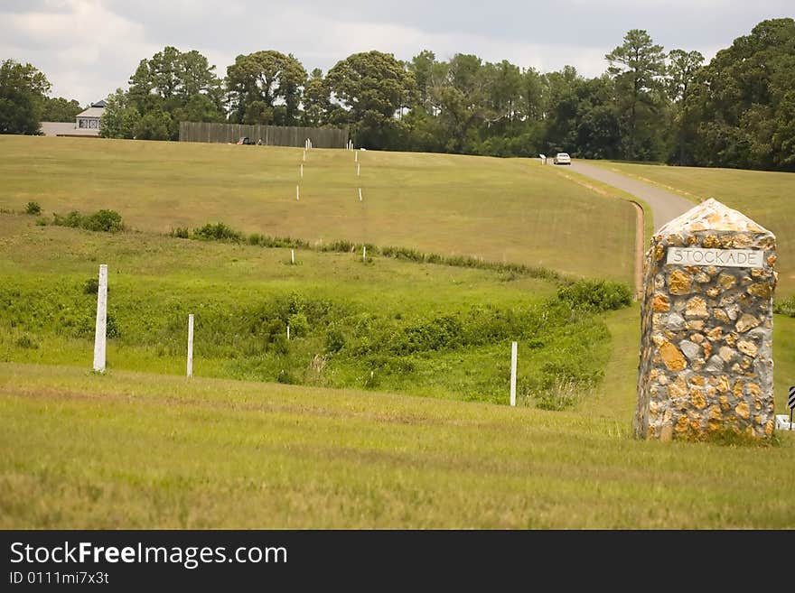 This stone marker sits on the site of the southeast corner of the Andersonville prison stockade during the Civil War. The line of white posts to the left marks the dead line. This stone marker sits on the site of the southeast corner of the Andersonville prison stockade during the Civil War. The line of white posts to the left marks the dead line.