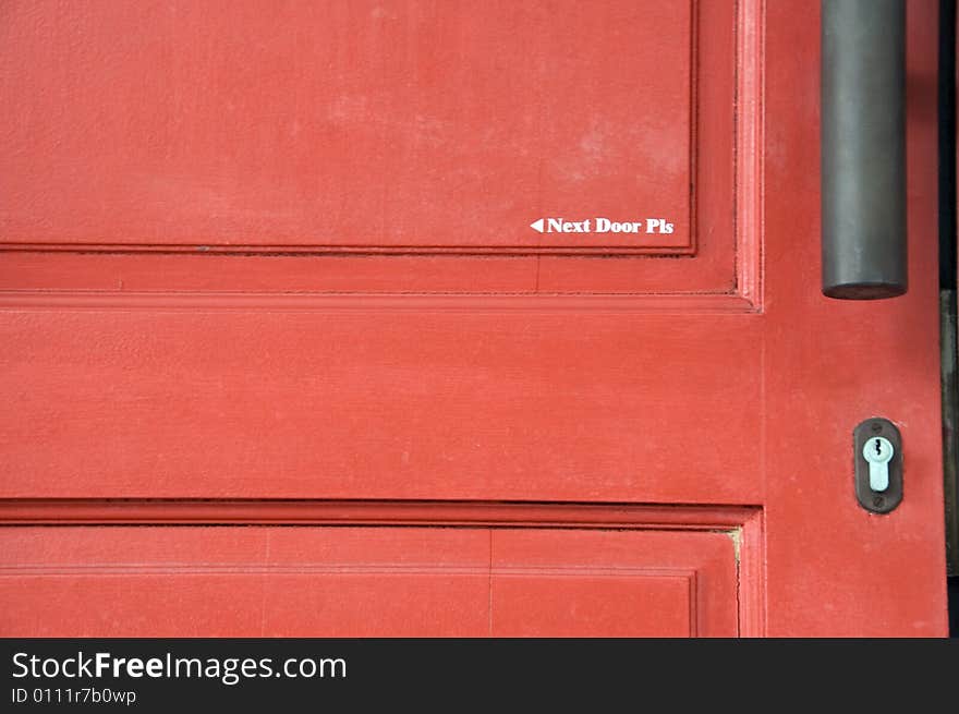 A door painted with words that says Next Door Please.