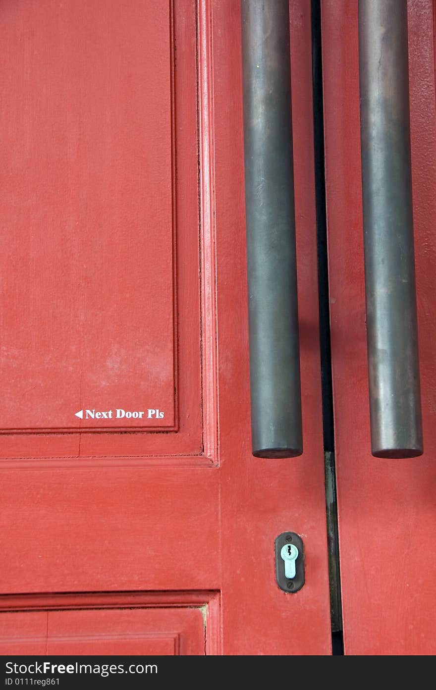 A door painted with words that says Next Door Please.