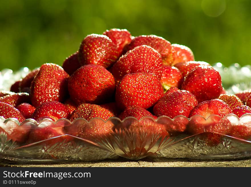 Bowl of sweet strawberries over a green summer background. Bowl of sweet strawberries over a green summer background