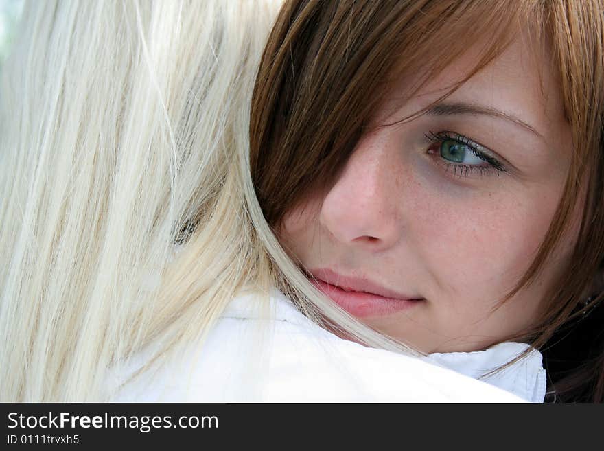 Young beautiful woman with a big green eyes put her head on the shoulder of the other, and looking somewhere thoughtfully