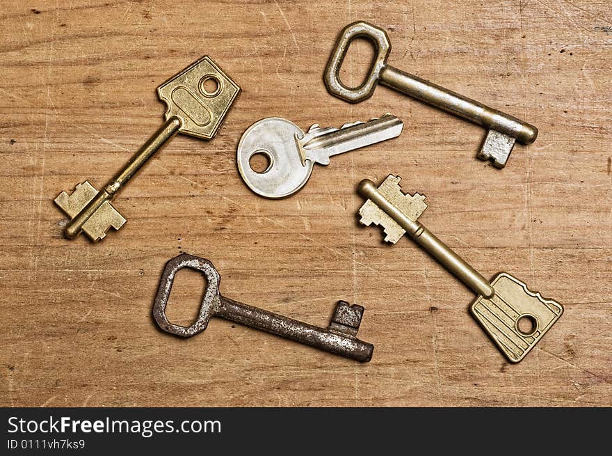 Assorted old keys on a wooden table.