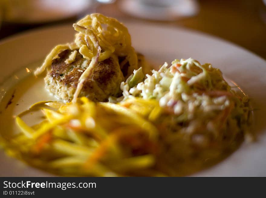 A delicious crab cake with cole slaw and fried onions. A delicious crab cake with cole slaw and fried onions.