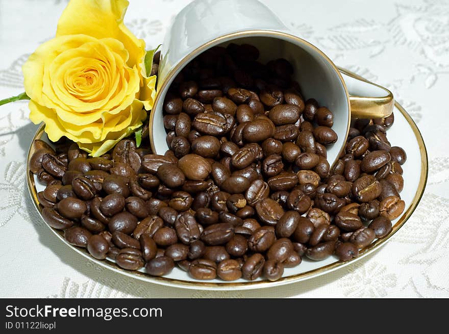 Coffee beans in fallen white retro cup with yellow rose. Coffee beans in fallen white retro cup with yellow rose