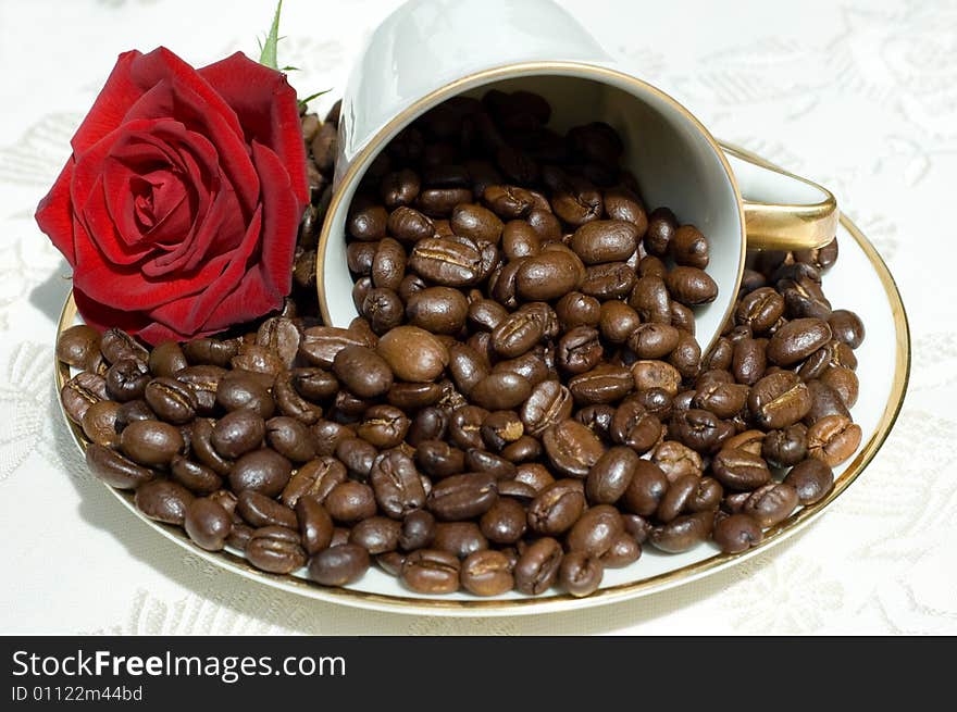 Coffee beans in fallen white retro cup with red rose. Coffee beans in fallen white retro cup with red rose