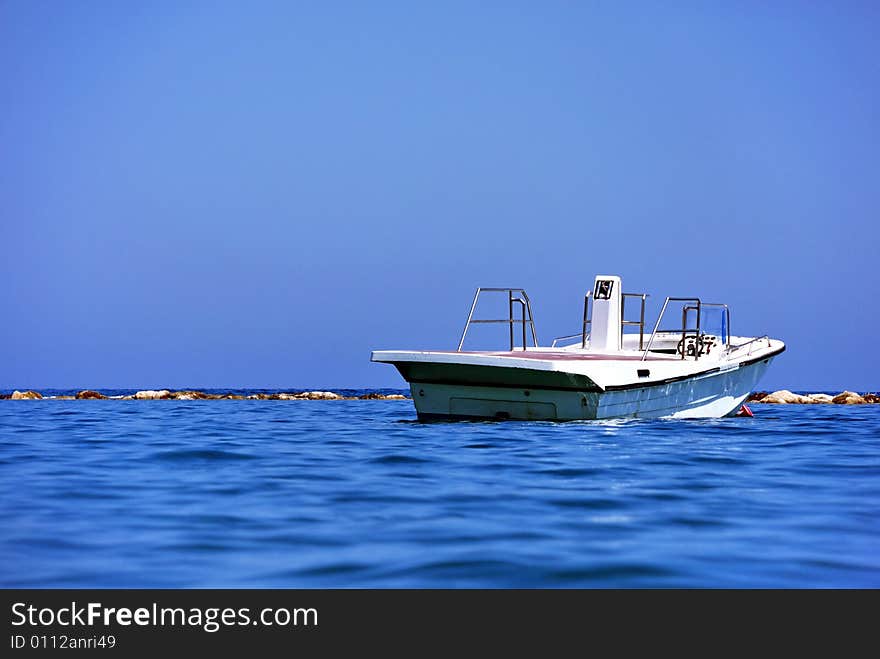 Boat on the Mediterranean sea against a background of rocks and blue sky