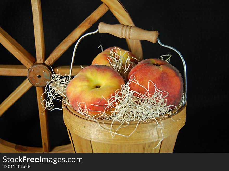 Peaches in a bushel basket with a wagon wheel. Peaches in a bushel basket with a wagon wheel.