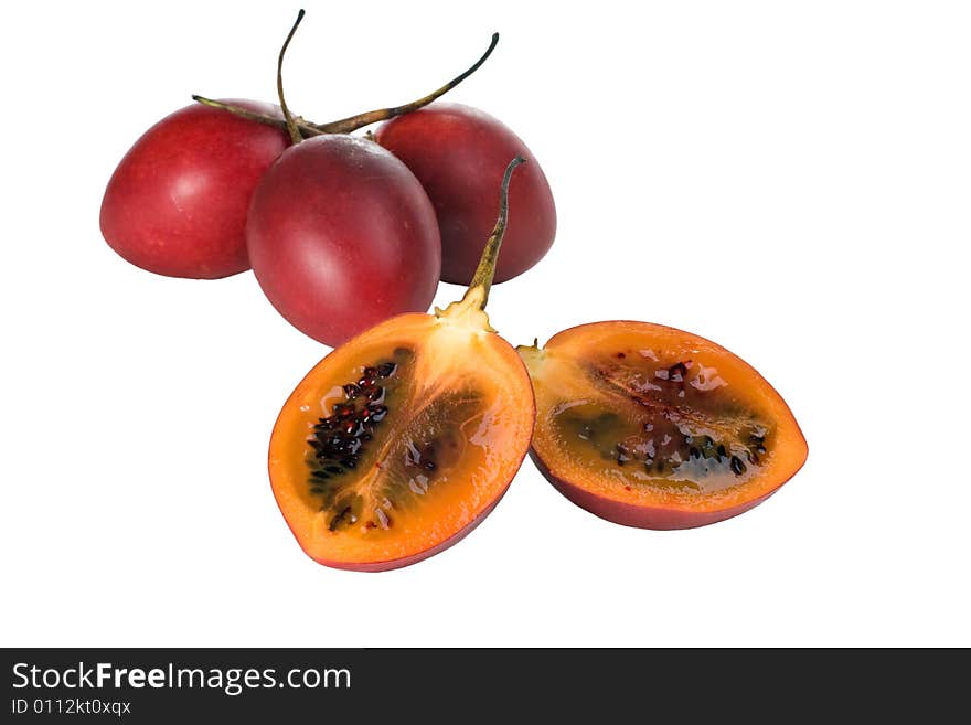 Whole and halved fresh Tamarillo fruit showing its deep red seeds and tangy sweet flesh. Whole and halved fresh Tamarillo fruit showing its deep red seeds and tangy sweet flesh