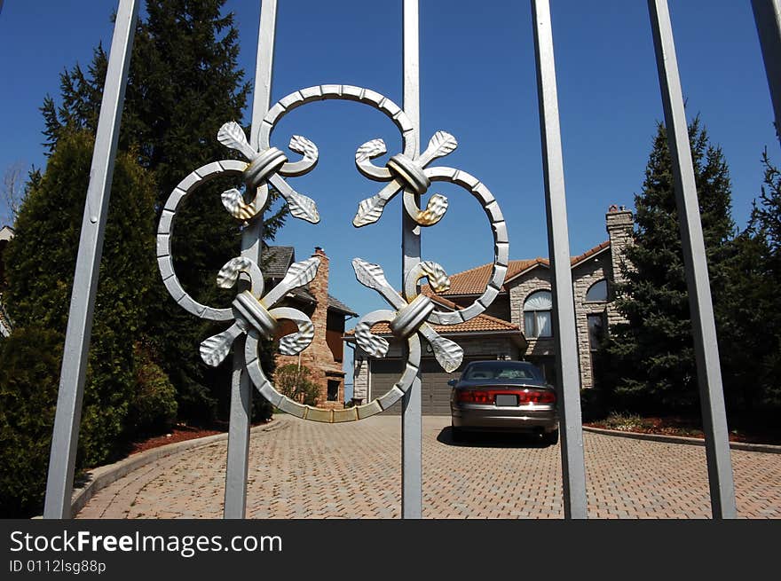An iron gate as entrance for a mansion in an rich neighborhood. An iron gate as entrance for a mansion in an rich neighborhood.