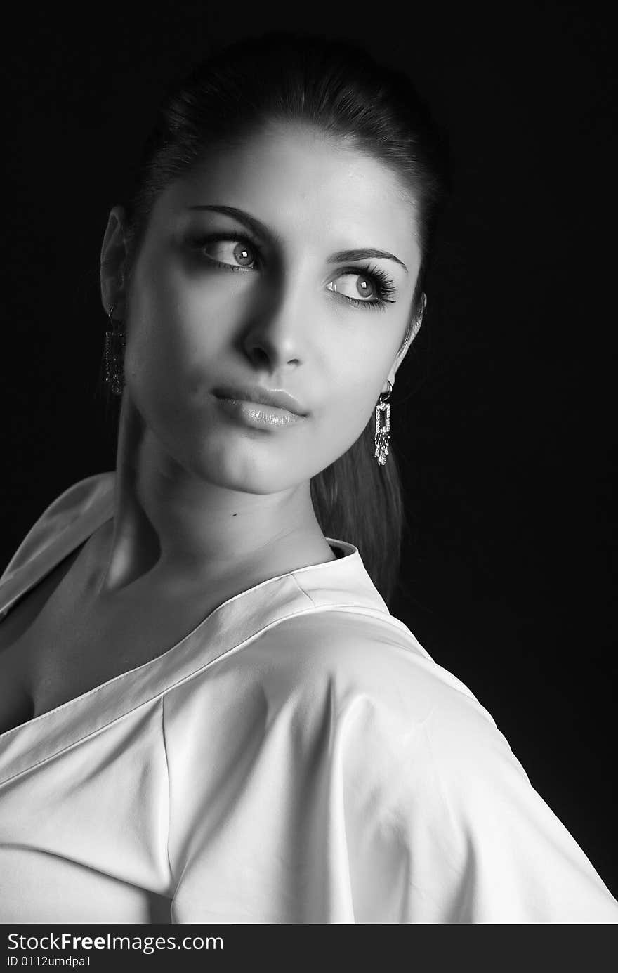 A young beautiful girl is dressed in white clothes at black background. A young beautiful girl is dressed in white clothes at black background