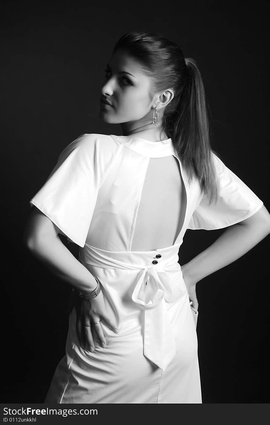 A young beautiful girl is dressed in white clothes at black background. A young beautiful girl is dressed in white clothes at black background