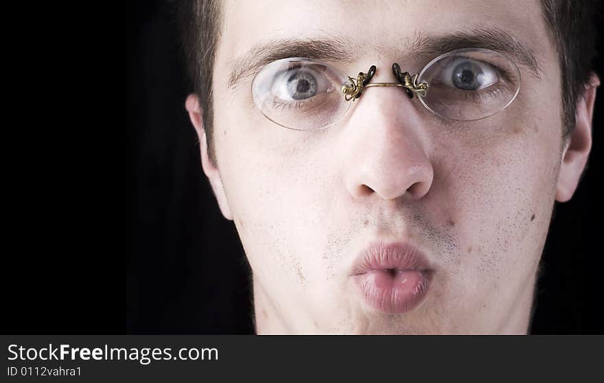 Surprised face of young man in glasses on a black background