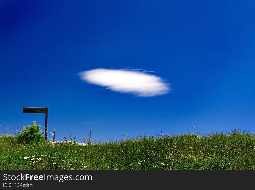 Cloud over green field with sign in background. Cloud over green field with sign in background