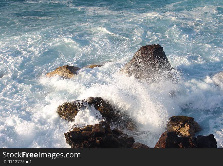 Waves breaking on the rocks in the blue ocean