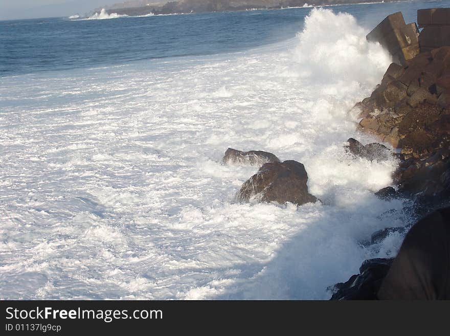 Waves breaking on the rocks in the blue ocean