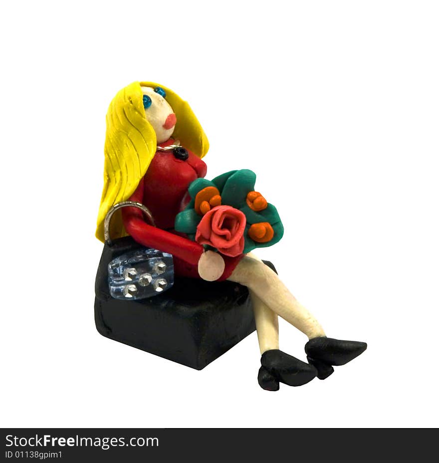 The plasticine blonde with a bouquet has a rest on a bench. The plasticine blonde with a bouquet has a rest on a bench