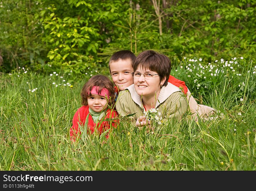 Woman and her kids laying in the spring grass. Woman and her kids laying in the spring grass